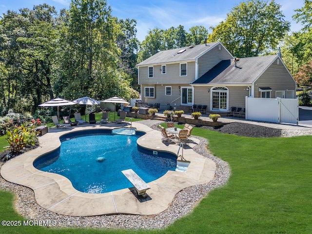 pool featuring fence, a diving board, a gate, a patio, and a yard