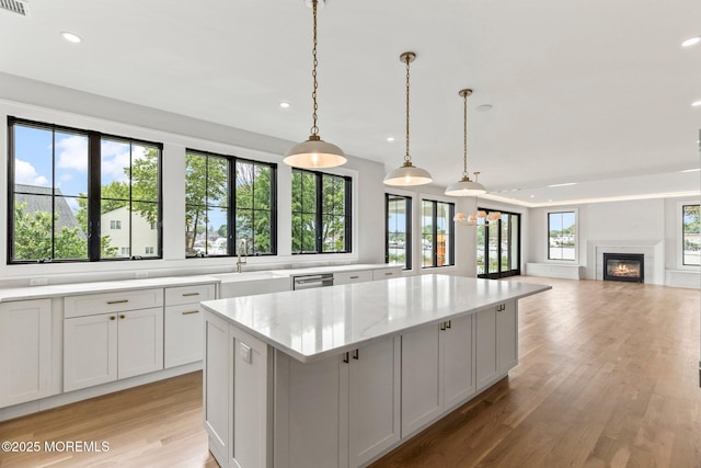 24 Baruch Dr, Long Branch, NJ 07740 - kitchen featuring a center island, light wood-style flooring, recessed lighting, a glass covered fireplace, and light stone countertops