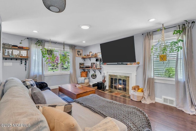living area featuring baseboards, visible vents, a wealth of natural light, and wood finished floors