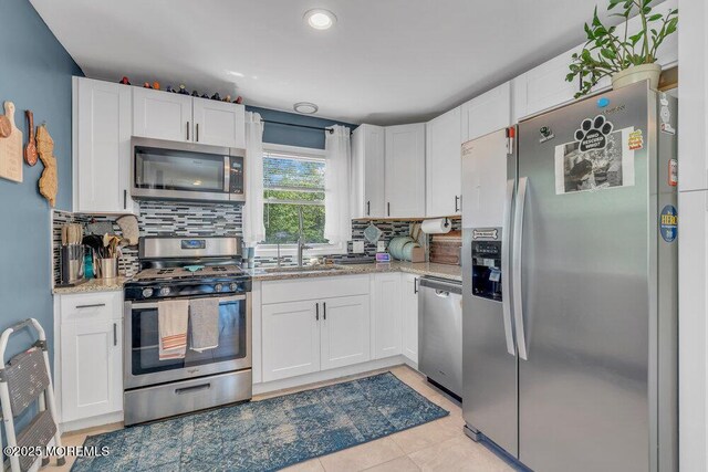 kitchen featuring backsplash, stainless steel appliances, and white cabinets