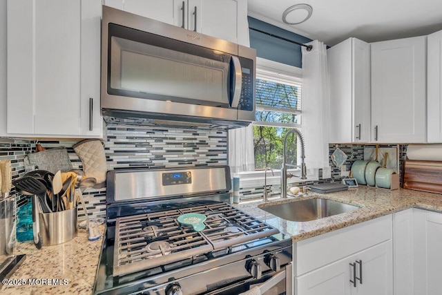 kitchen featuring a sink, decorative backsplash, stainless steel appliances, and white cabinetry