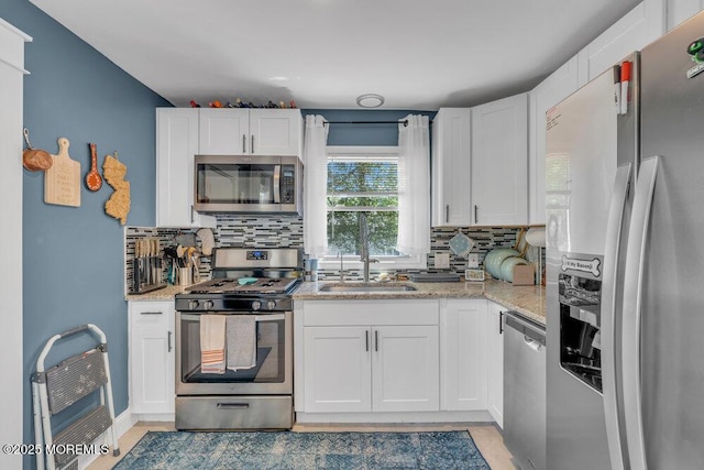 kitchen with white cabinets, appliances with stainless steel finishes, decorative backsplash, and a sink