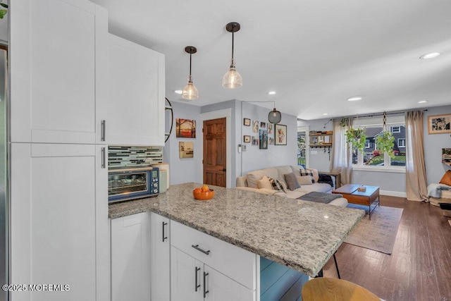 kitchen with tasteful backsplash, a toaster, white cabinets, a peninsula, and open floor plan