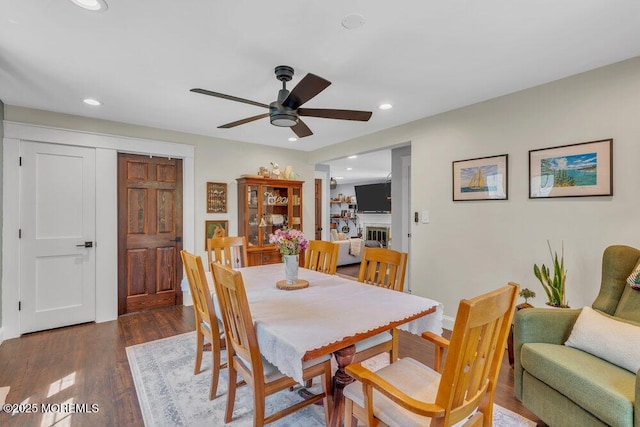 dining room with ceiling fan, a glass covered fireplace, recessed lighting, baseboards, and wood finished floors