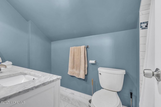 bathroom featuring vaulted ceiling, vanity, baseboards, toilet, and marble finish floor