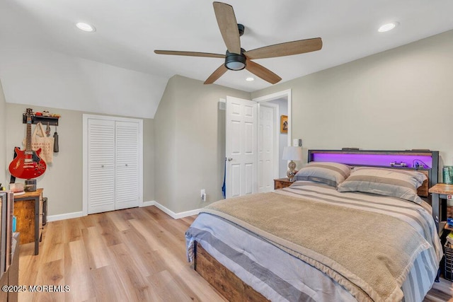 bedroom with a closet, baseboards, light wood-type flooring, recessed lighting, and vaulted ceiling