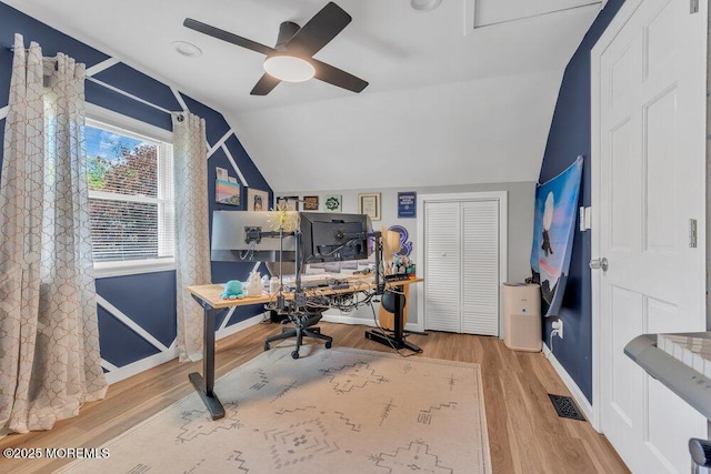 home office with a ceiling fan, baseboards, wood finished floors, lofted ceiling, and visible vents