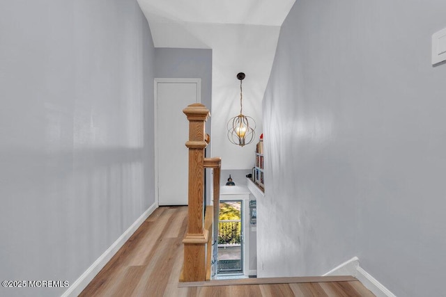 stairs featuring baseboards, wood finished floors, and a chandelier