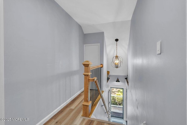 stairs with baseboards, an inviting chandelier, and wood finished floors