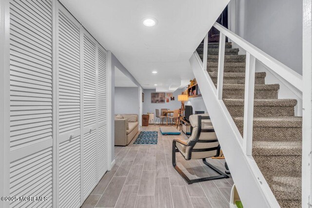 corridor featuring recessed lighting, wood finished floors, and stairway