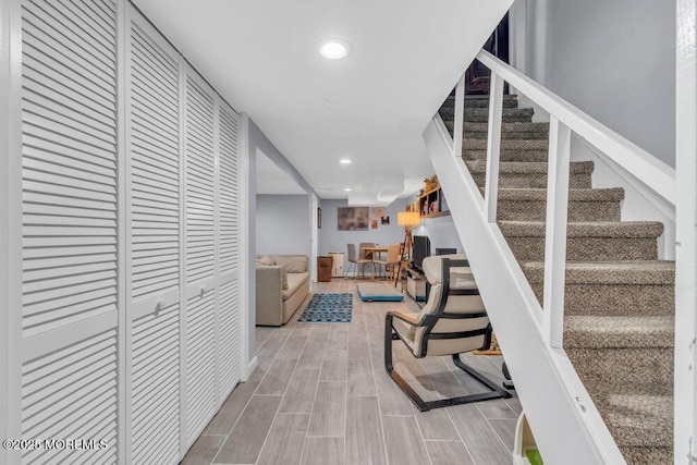 corridor featuring recessed lighting, wood finished floors, and stairway