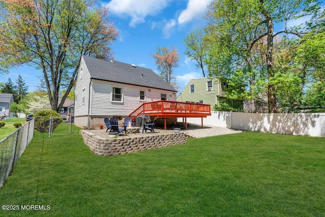back of house featuring a deck, a fenced backyard, a gate, a lawn, and a fire pit