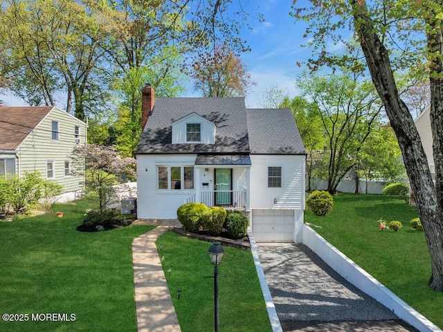 new england style home with driveway, a chimney, a front yard, a garage, and fence