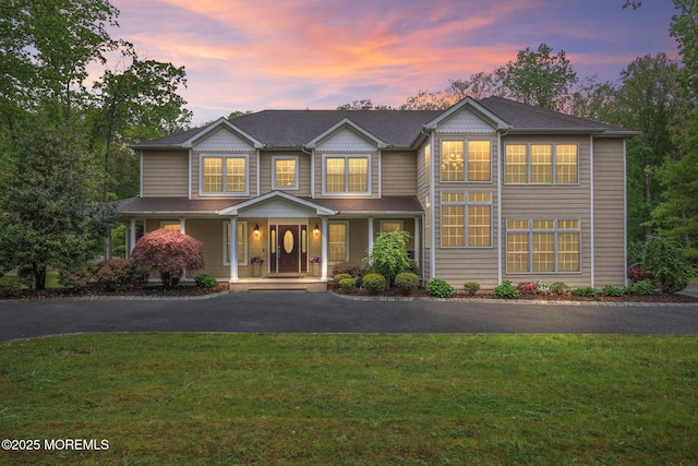 view of front of house featuring a porch, a front yard, and asphalt driveway