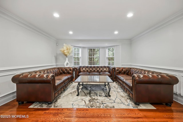 living room with crown molding, wood finished floors, a wainscoted wall, recessed lighting, and a decorative wall