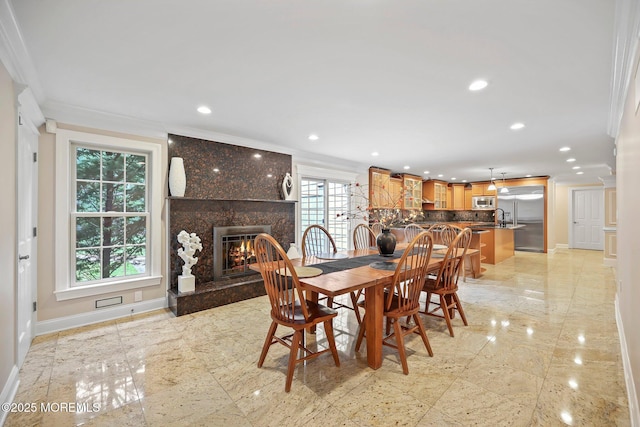 dining area with crown molding, baseboards, a fireplace, and recessed lighting