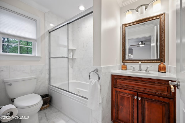 bathroom with tile walls, marble finish flooring, bath / shower combo with glass door, vanity, and toilet