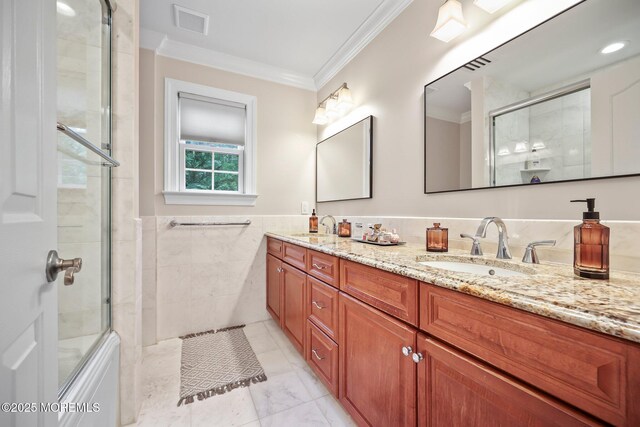 full bathroom with crown molding, tile walls, an enclosed shower, double vanity, and a wainscoted wall