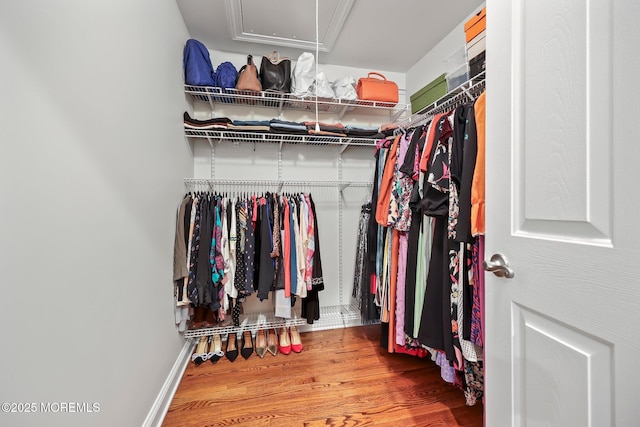 walk in closet with wood finished floors and attic access