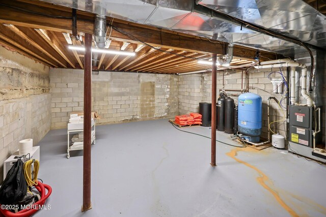 unfinished below grade area featuring a water pressure tank and heating unit