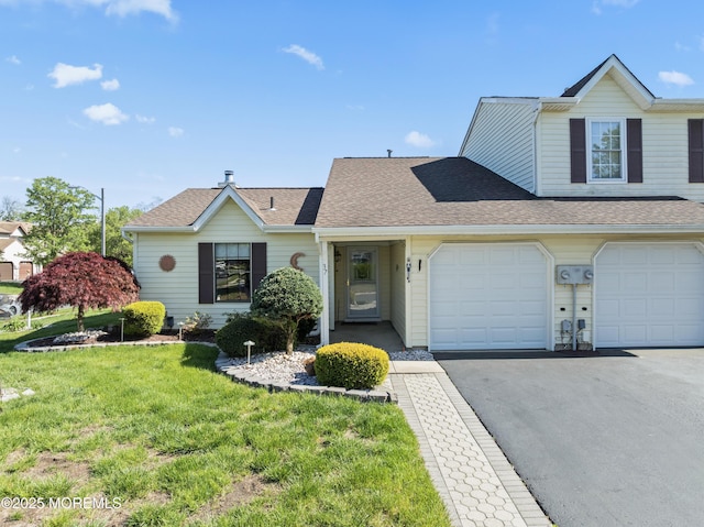 view of front of house with a front yard, aphalt driveway, and a shingled roof