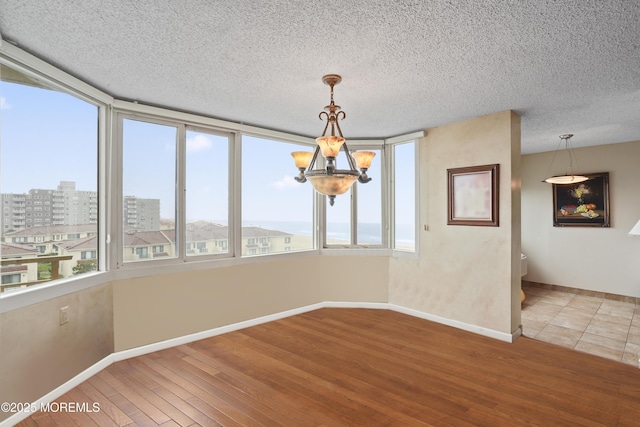 717 Ocean Ave Unit 512, Long Branch, NJ 07740 - unfurnished dining area with a chandelier, healthy amount of natural light, baseboards, wood finished floors, and a textured ceiling