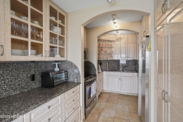 717 Ocean Ave Unit 512, Long Branch, NJ 07740 - kitchen with a textured ceiling, decorative backsplash, dark stone counters, arched walkways, and appliances with stainless steel finishes
