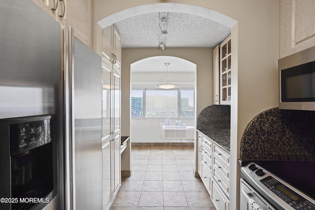 717 Ocean Ave Unit 512, Long Branch, NJ 07740 - kitchen featuring stainless steel appliances, arched walkways, a textured ceiling, baseboards, and glass insert cabinets