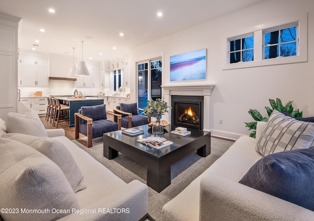 living room with recessed lighting, a warm lit fireplace, and baseboards