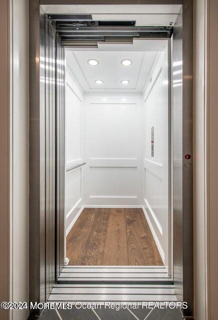 room details with recessed lighting, elevator, and wood finished floors
