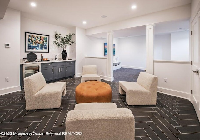 living area featuring indoor wet bar, recessed lighting, baseboards, and decorative columns