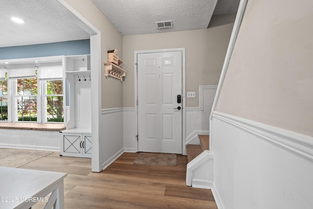 interior space featuring light wood-style floors, baseboards, a textured ceiling, and visible vents