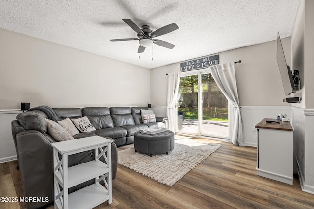 living room featuring a ceiling fan, a textured ceiling, and wood finished floors
