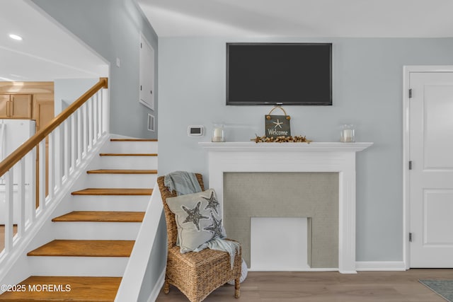 stairway with baseboards, visible vents, wood finished floors, and a fireplace
