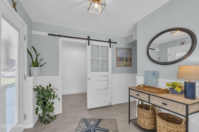 interior space featuring visible vents, a barn door, and wainscoting