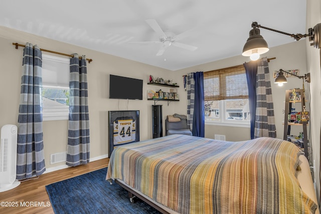 bedroom with baseboards, ceiling fan, wood finished floors, and multiple windows