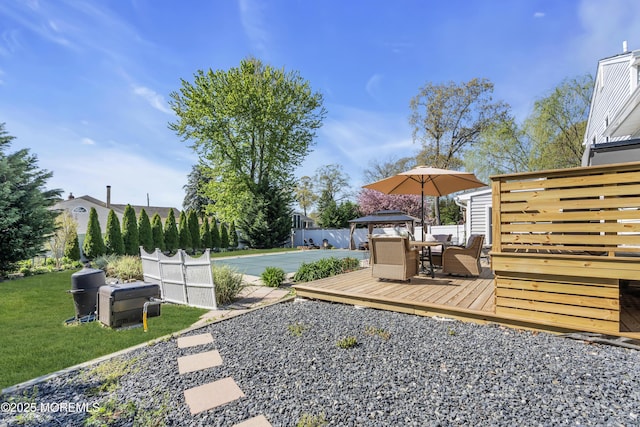 view of yard featuring a deck, fence, and outdoor dining area