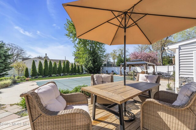 wooden terrace with fence, outdoor dining space, a gazebo, a patio, and a pool