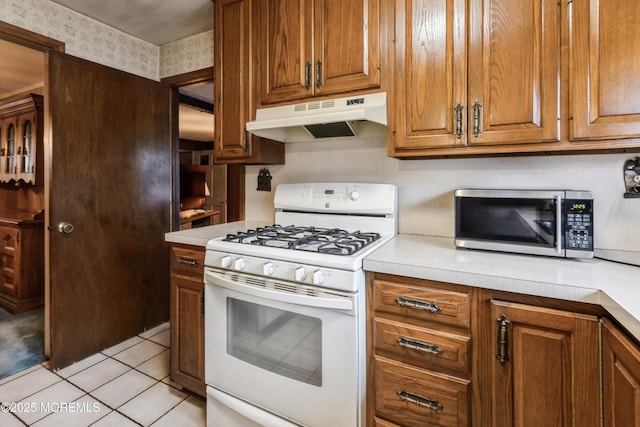 2174 Begonia Ave, Sea Girt, NJ 08750 - kitchen with under cabinet range hood, white gas range oven, stainless steel microwave, and light countertops