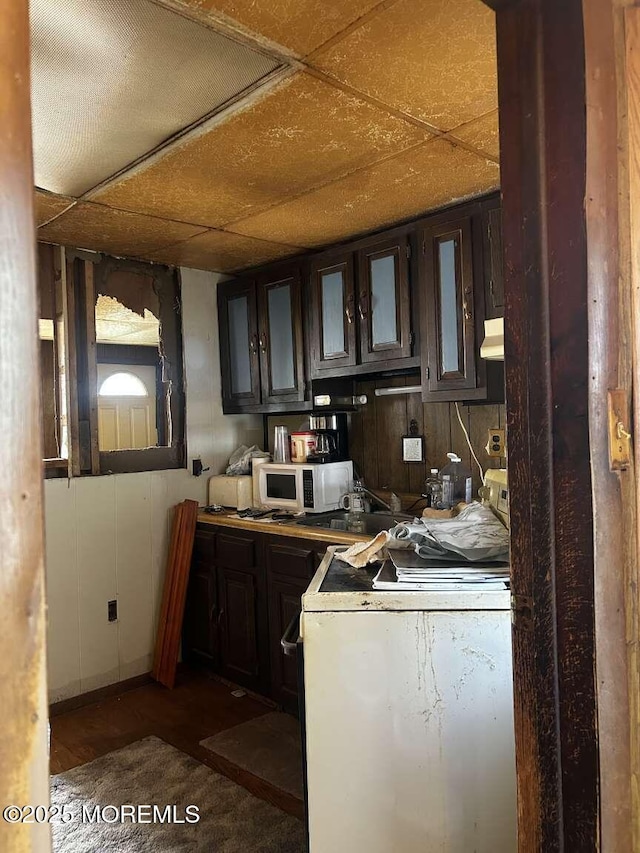 kitchen with washer / clothes dryer, glass insert cabinets, dark brown cabinetry, a paneled ceiling, and white microwave