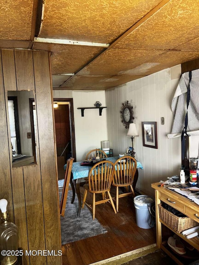 dining area featuring wood finished floors and wooden walls