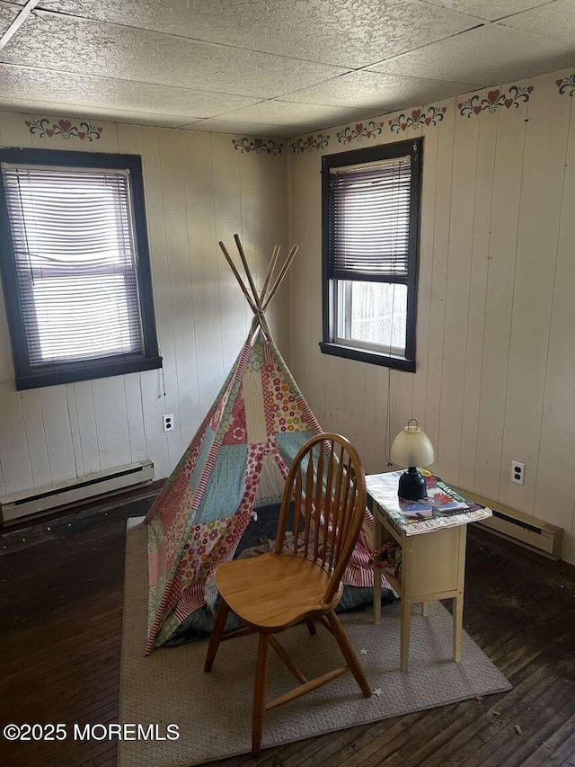 game room with baseboard heating, wooden walls, and hardwood / wood-style floors