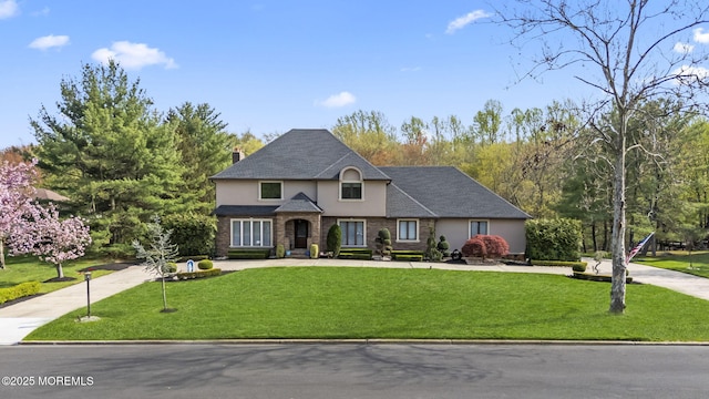 view of front of property with driveway, a chimney, a front lawn, and stucco siding