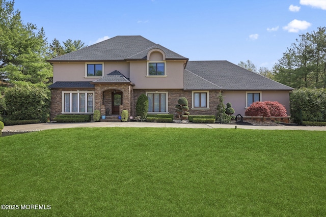traditional-style home with a shingled roof, stucco siding, and a front yard