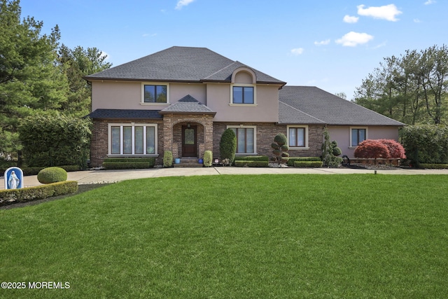 view of front of house featuring a shingled roof, stucco siding, and a front yard