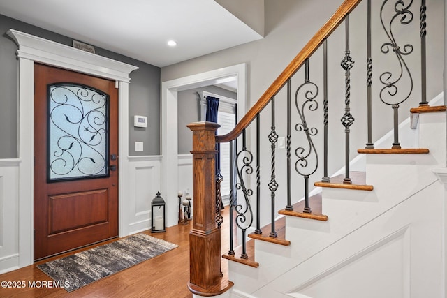 foyer with stairs, wainscoting, a decorative wall, wood finished floors, and recessed lighting