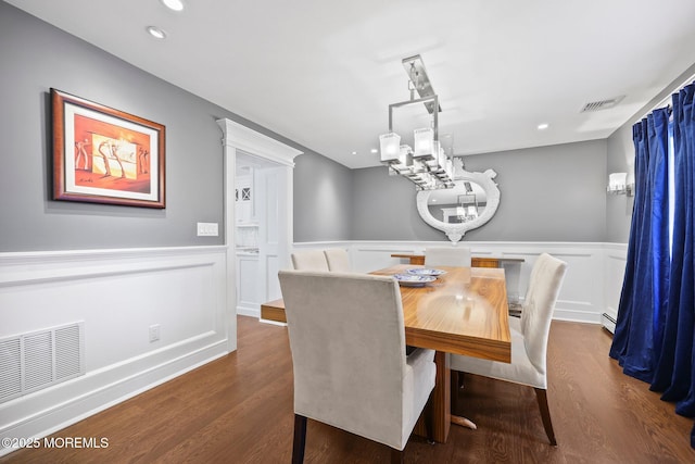 dining space with a notable chandelier, visible vents, dark wood-style floors, and a wainscoted wall