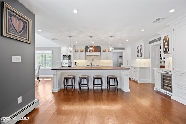 kitchen featuring tasteful backsplash, a baseboard heating unit, wine cooler, stainless steel oven, and recessed lighting