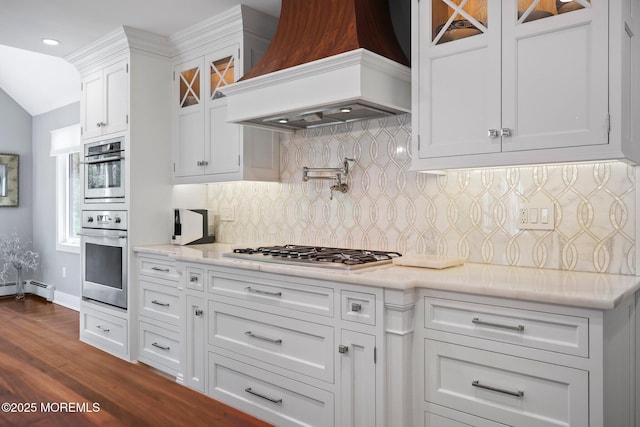 kitchen featuring dark wood finished floors, white cabinets, custom exhaust hood, glass insert cabinets, and stainless steel appliances