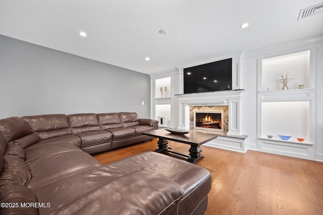 living area with a premium fireplace, visible vents, wood finished floors, and recessed lighting